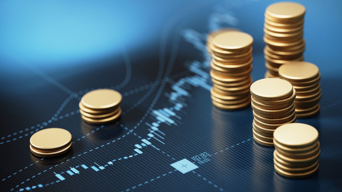 Coin stacks sitting on blue financial graph background.