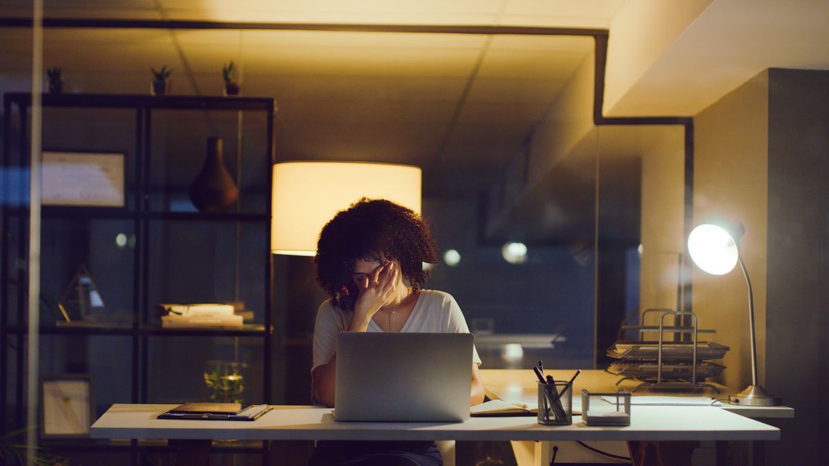 Shot of a young businesswoman looking stressed while using a laptop during a late night at work.