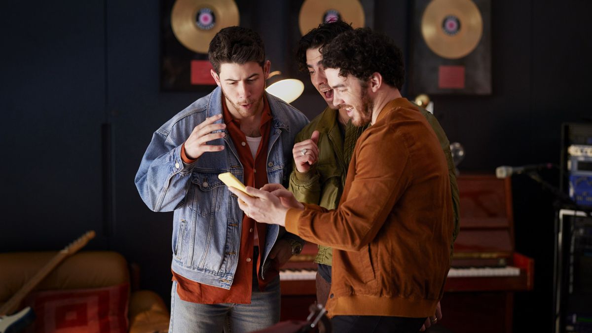 The Jonas Brothers gathered around a phone playing Candy Crush Saga as part of a gaming partnership.