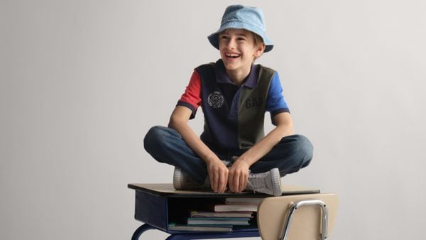 A kid sitting on top of a desk as part of a campaign image for Gap's back-to-school marketing.