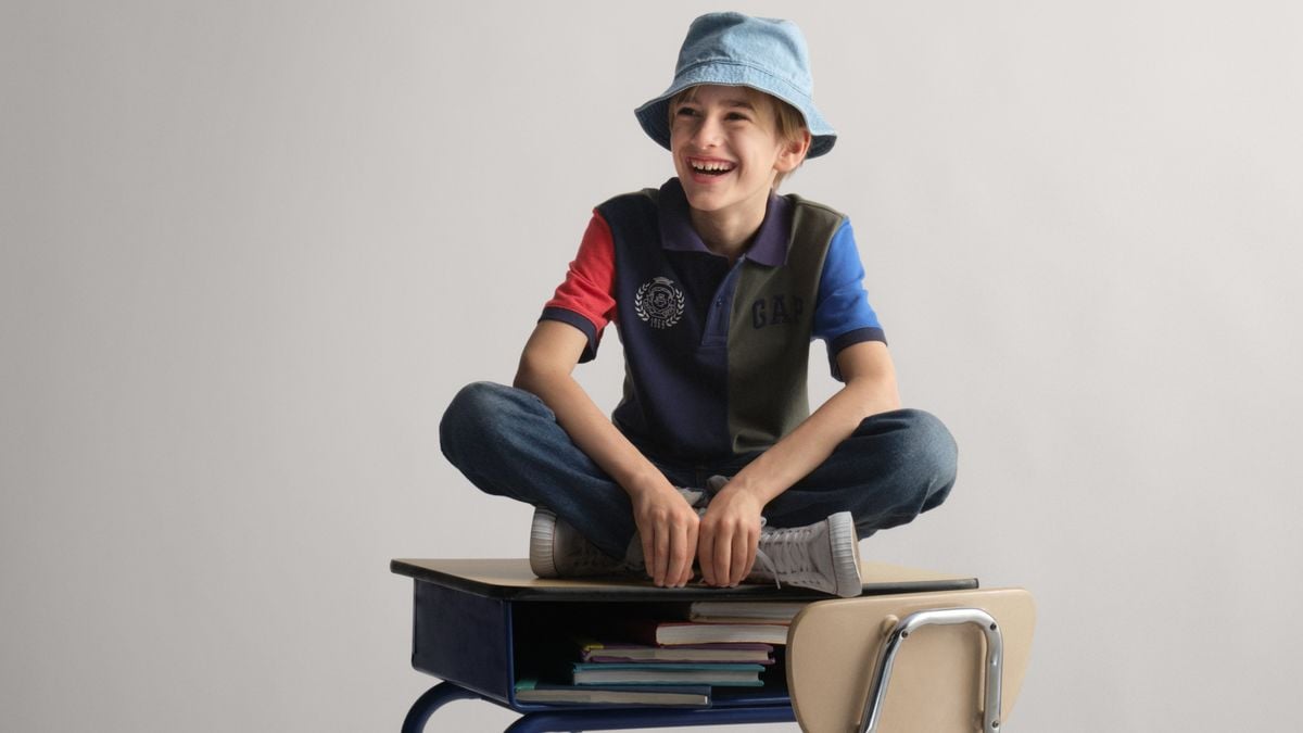 A kid sitting on top of a desk as part of a campaign image for Gap's back-to-school marketing.